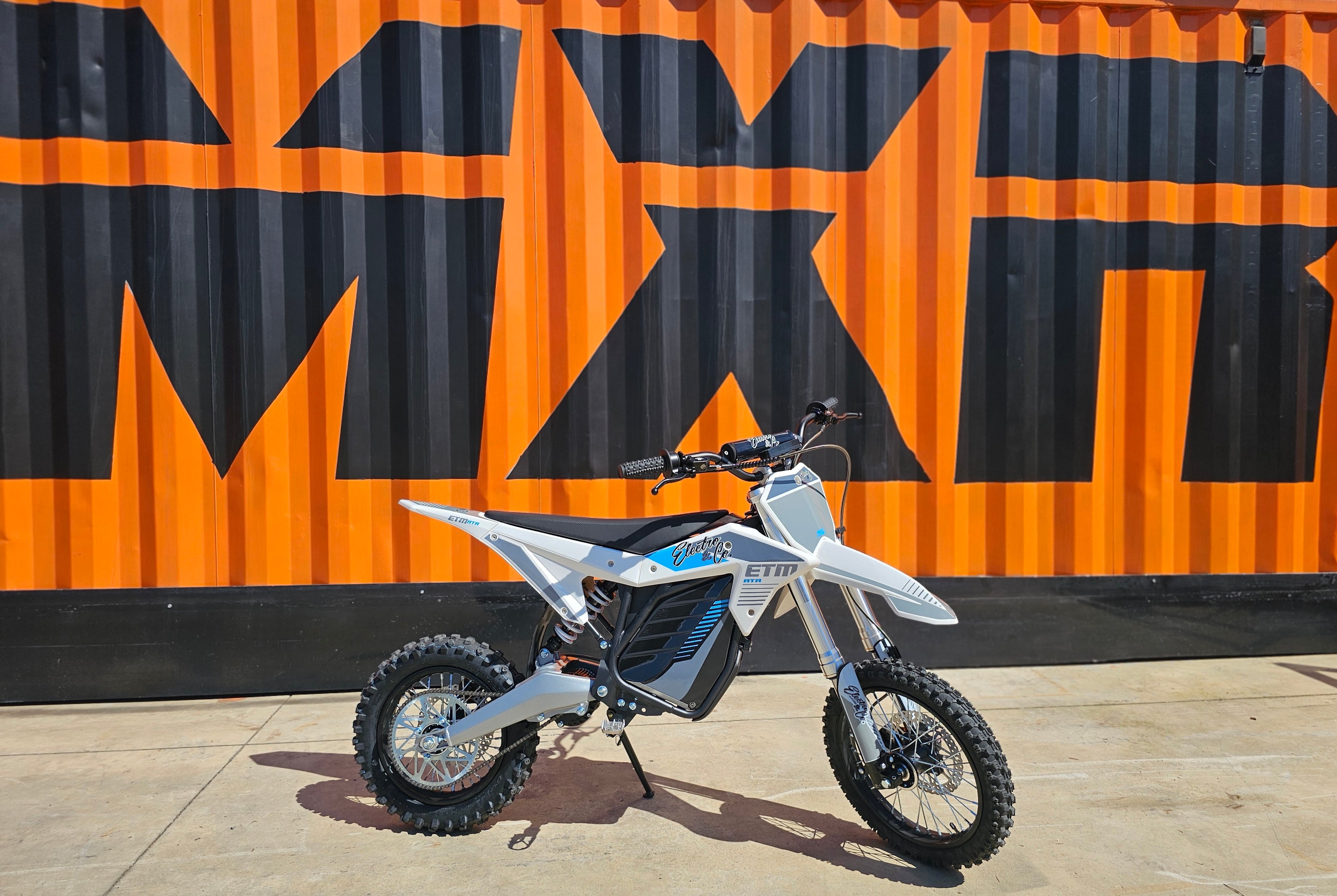 Motorcycle parked in front of a large orange and black 'MXR' sign.
